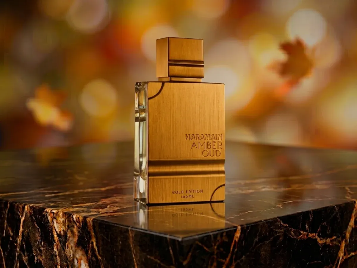 Bottle of Al Haramain Amber Oud Gold Edition on dark marble with autumn leaves