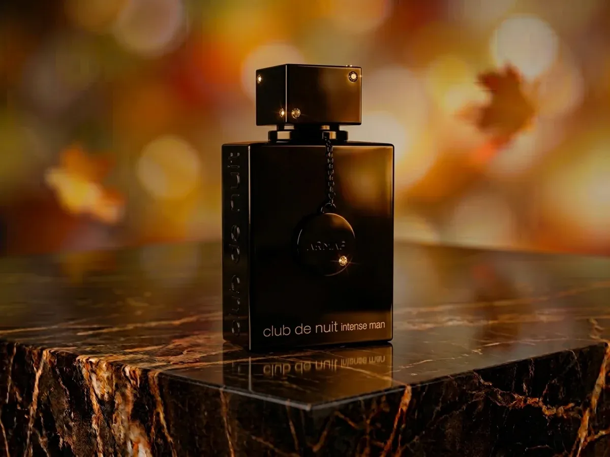 Bottle of Armaf Club de Nuit Intense Man on dark marble with autumn leaves