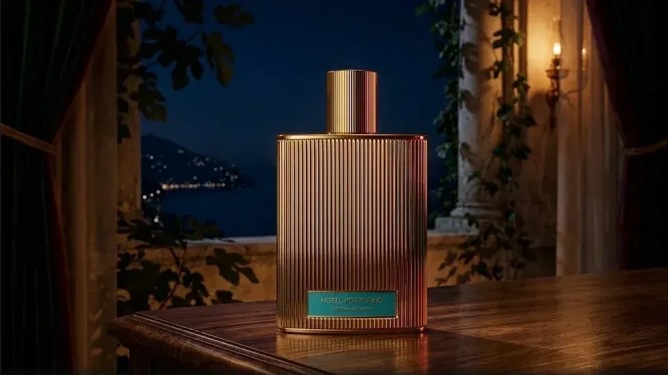 Frasco de Hotel Portofino Extrait de Parfum de Victoria Beckham Beauty en una galería frente al mar, de noche.