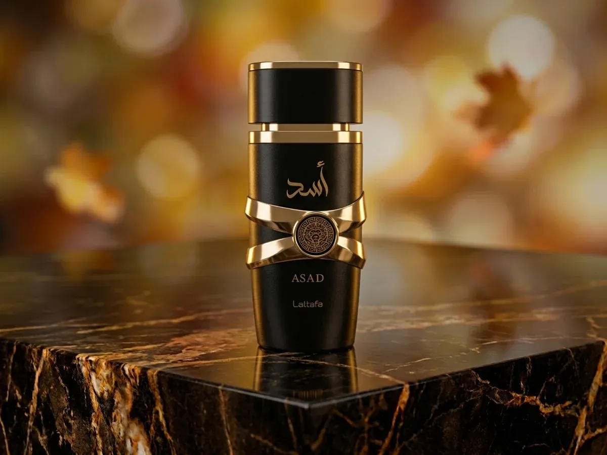 Bottle of Lattafa Asad on dark marble with autumn leaves